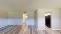 Located at 464 Brentwood Dr in Daytona Beach, Florida, this single-story, one-bedroom, one-bathroom unit offers a practical and well-organized layout across a comfortable footprint. Throughout the space, light-toned luxury vinyl plank flooring provides a clean, cohesive look that ties each room together seamlessly.

The living room serves as the central gathering area, featuring multiple windows that invite ample natural light and neutral gray walls that complement the flooring. A front entry door flanked by windows creates a bright, welcoming entry point. The space flows through hallways that connect to the remaining rooms efficiently.

The galley-style kitchen is equipped with white cabinetry, a black electric range, and a full-size black refrigerator, offering a functional cooking environment with generous cabinet storage above and below the countertops.

The spacious bedroom features a large closet with sliding doors, a natural light-filled window with blinds, and the same consistent flooring found throughout. A second closet provides additional storage elsewhere in the unit.

The full bathroom includes a tub/shower combination, toilet, and a single-sink vanity, all finished in clean white tones. Textured ceilings are present throughout, and central air vents are visible in each room, ensuring year-round climate control.