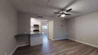 This single-floor residence offers a thoughtfully updated interior with a cohesive, modern design. The open living area serves as the heart of the space, finished with durable wood-look plank flooring in a warm neutral tone and a ceiling fan with integrated lighting. A large window allows natural light to fill the room, while a front entry door provides convenient access. The textured ceiling adds a classic touch consistent throughout the common areas.

The kitchen is efficiently designed with white shaker-style cabinetry, a white subway tile backsplash, and dark countertops that provide a clean contrast. Stainless steel appliances include an electric range, over-the-range microwave, and a refrigerator. A pass-through counter connects the kitchen to the living area, enhancing the open feel. Track lighting overhead ensures ample task illumination.

The bedroom features its own ceiling fan, soft neutral walls, wood-look flooring, and a built-in closet with shelving. A dedicated laundry area accommodates a stacked washer and dryer unit and includes a window for natural light. The bathroom is finished with a white vanity offering generous drawer storage, a framed mirror, brushed nickel hardware, and wood-look flooring, presenting a clean and contemporary appearance.