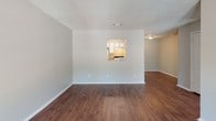 This single-story, 2-bedroom, 1-bathroom unit is thoughtfully laid out to maximize comfort and functionality. Rich, dark hardwood-style flooring flows consistently throughout the entire space, adding warmth and cohesion to every room. Textured ceilings and neutral gray walls provide a clean, versatile backdrop throughout.

The living area is bright and open, featuring a large window with vertical blinds that invites ample natural light and offers outdoor views of surrounding greenery. A distinctive pass-through window connects the living and dining area to the kitchen, enhancing the sense of openness between spaces.

The galley-style kitchen is efficiently designed with light wood cabinetry, laminate countertops, a stainless steel sink, and white appliances including a refrigerator and range. The layout allows for smooth workflow within the cooking space.

Both bedrooms are well-proportioned, each featuring hardwood-style flooring, neutral walls, and large windows that frame outdoor views. One bedroom includes a closet with open access, providing practical storage.

The full bathroom is finished with a tub-shower combination, a toilet, and a vanity with a laminate countertop, offering a clean and functional design. The unit's single-floor layout ensures easy accessibility and a seamless flow throughout all living areas.