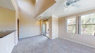 This two-story residence offers a well-organized layout with a warm, neutral color palette of soft beige tones throughout. The main living area is immediately impressive with its soaring vaulted ceilings, ceiling fan, and track lighting, creating an open and airy atmosphere. Mirrored sliding closet doors and large windows allow natural light to flow freely, offering views of the surrounding neighborhood greenery.

The kitchen is equipped with ample honey-toned wood cabinetry, dark speckled countertops, tile flooring, and black appliances including a range and built-in microwave, providing a practical and efficient workspace.

The bedrooms are carpeted and generously sized, each featuring ceiling fans and windows that bring in abundant natural light. One bedroom includes a sliding mirrored closet with built-in shelving and hanging rods for organized storage. An upper-level loft-style space with a built-in desk area offers flexibility as a home office or study nook, complete with exterior-facing windows.

The bathroom features tile flooring, a wide vanity with warm wood cabinetry, a large mirror with overhead lighting, and a full tub-shower combo. Throughout the residence, consistent finishes and carpeted floors on both levels contribute to a cohesive and comfortable living environment.
