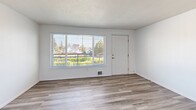 Located at 3302 Pacific Ave in Tacoma, WA, this one-bedroom, one-bathroom unit offers a well-organized, single-level layout designed for comfortable everyday living. The open living area greets you upon entry, featuring light-toned luxury vinyl plank flooring and a large picture window that fills the space with natural light and provides views of the surrounding neighborhood. The kitchen is accessible via a pass-through counter that doubles as a breakfast bar, creating a connected feel between the cooking and living areas. Inside, the kitchen is equipped with stainless steel appliances—including a full-size refrigerator, electric range, and dishwasher—complemented by grey cabinetry, white countertops, and overhead fluorescent lighting. The bedroom offers plush wall-to-wall carpeting, a window overlooking greenery, and generous storage provided by dual sliding closets. The full bathroom features wood-look LVP flooring, a tiled tub and shower surround in warm neutral tones, a vanity with under-sink storage, and clean white fixtures throughout. The unit's consistent light and bright color palette, white walls, and modern finishes create a clean, move-in-ready aesthetic throughout.
