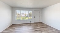 Located at 3302 Pacific Ave in Tacoma, WA, this one-bedroom, one-bathroom unit offers a well-organized, single-level layout designed for comfortable everyday living. The open living area greets you upon entry, featuring light-toned luxury vinyl plank flooring and a large picture window that fills the space with natural light and provides views of the surrounding neighborhood. The kitchen is accessible via a pass-through counter that doubles as a breakfast bar, creating a connected feel between the cooking and living areas. Inside, the kitchen is equipped with stainless steel appliances—including a full-size refrigerator, electric range, and dishwasher—complemented by grey cabinetry, white countertops, and overhead fluorescent lighting. The bedroom offers plush wall-to-wall carpeting, a window overlooking greenery, and generous storage provided by dual sliding closets. The full bathroom features wood-look LVP flooring, a tiled tub and shower surround in warm neutral tones, a vanity with under-sink storage, and clean white fixtures throughout. The unit's consistent light and bright color palette, white walls, and modern finishes create a clean, move-in-ready aesthetic throughout.
