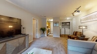 Located at 705 Powers Ferry Rd SE in Marietta, GA, this single-floor residence offers a thoughtfully laid-out living space with a blend of comfort and functionality. The open living area is generously sized, featuring soft carpeting underfoot and track lighting overhead, creating a warm and inviting atmosphere. Large windows allow natural light to fill the room, offering views of the surrounding greenery. The space flows seamlessly toward the kitchen, which is equipped with warm wood cabinetry, light countertops, an electric range, and a refrigerator — all set on rich hardwood-style flooring that adds a classic touch. A dedicated in-unit laundry area with a full-size washer and dryer is conveniently accessible from the main living space, adding everyday practicality. The bedrooms are well-proportioned, each featuring plush carpeting, ceiling fans, and windows that frame outdoor views. The primary bedroom offers ample space for a large bed and furnishings, accompanied by a bathroom with a wood-vanity and a full tub-shower combination. Hardwood-style flooring extends through the bathroom and hallway areas. Throughout the residence, neutral tones and clean architectural lines create a cohesive, comfortable ambiance suited for everyday living.