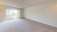 Located at 2101 Prior Rd in Wilmington, Delaware, this single-floor residence offers a practical and comfortable layout with a clean, neutral aesthetic throughout. The living area is generously sized, featuring wall-to-wall carpeting and a sliding glass door that opens to a private balcony, allowing natural light to fill the room. A chandelier anchors the adjoining dining area, adding a subtle decorative touch to the open layout. The bedroom is a well-proportioned, carpeted room with its own door and a sliding glass door providing additional outdoor access and natural light. Vertical blinds on the sliding doors offer privacy and light control throughout. The kitchen is thoughtfully equipped with light wood cabinetry, dark granite-style countertops, and black appliances including a gas range with oven and an over-the-range microwave. The tile flooring in the kitchen provides a practical contrast to the carpeted living spaces. The bathroom features a full tub-and-shower combination, a single vanity with under-sink storage, tile flooring, and a round mirror with overhead lighting. Neutral tones and textured ceilings are consistent throughout the space, creating a cohesive and move-in-ready environment.
