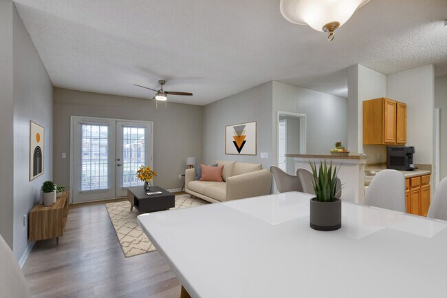 Comedor con vista a la sala de estar Dunwoody Place con ventanas grandes, pisos de madera clara, tonos neutros y un diseño luminoso y cómodo en un apartamento asequible con ingresos restringidos en Huntsville, AL. - Dunwoody Place
