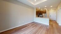 Located at 1 E Pearl St in Burlington, NJ, this single-floor residence offers a thoughtfully designed layout with modern finishes throughout. The kitchen is a standout feature, equipped with rich dark-stained cabinetry reaching toward the ceiling, granite countertops, a subway tile backsplash, and a full suite of stainless steel appliances including a gas range, over-the-range microwave, dishwasher, and refrigerator. Light hardwood-style flooring runs throughout the main living areas, complementing the neutral color palette and recessed lighting overhead. The open-concept living and dining area benefits from natural light streaming through sliding glass doors that lead to an outdoor balcony, while a tray ceiling adds an elevated architectural detail to the space. The bedrooms are finished with plush carpeting, tray ceilings, and ample natural light from windows with outdoor views. One bedroom includes a walk-in closet, providing generous storage. The bathroom is generously sized, featuring large-format tile flooring, a wide double-sink vanity with dark cabinetry, a well-lit mirror, and a tiled walk-in shower. Clean lines, consistent finishes, and a bright, neutral atmosphere define the overall ambiance of this well-appointed residence.