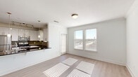Located at 1750 FM-423 S in Little Elm, TX, this well-appointed one-bedroom, one-bathroom unit offers a thoughtfully designed single-floor layout. Light wood-style flooring runs throughout, complementing the bright, neutral color palette that gives the space an open and airy feel.

The combined kitchen and living area forms the heart of the unit. The kitchen features sleek white cabinetry with modern bar-pull hardware, dark granite countertops, a gray subway tile backsplash, stainless steel appliances including a refrigerator, range, and microwave, and a peninsula with pendant lighting that doubles as a breakfast bar. The living area receives generous natural light through multiple windows fitted with blinds, and a private entry door adds convenience.

The bedroom is a comfortable retreat with a ceiling fan, a walk-in closet with built-in shelving, and windows that invite additional natural light. Adjacent to the bedroom, the bathroom is finished with a dark granite vanity top, white cabinetry, a large mirror with vanity lighting, a tiled soaking tub and shower combination, and mosaic accent tile detailing.

Clean architectural lines, consistent modern finishes, and a well-organized floor plan make this unit a practical and attractive living space in Little Elm.