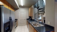 This two-story space offers a well-organized and functional layout designed to comfortably accommodate multiple guests. The kitchen is efficiently arranged with warm wood cabinetry, dark countertops, a double stainless steel sink, and full appliances, including a refrigerator and stove. A louvered-door pantry or utility closet adds practical storage. A striking black metal spiral staircase serves as both a functional and architectural focal point, connecting the two floors with a sense of style.

The living area on the main floor features hardwood-style flooring, a plush sofa with colorful accent pillows, and large sliding glass doors framed by sheer curtains that invite natural light and provide views to the exterior. The space is accented with contemporary wall art, adding a modern touch to the overall ambiance.

The sleeping quarters are spread across both floors and include rooms with multiple bunk beds — some with two sets — offering generous sleeping capacity. Each bedroom features hardwood-style floors, ceiling fans, and windows that allow natural light. The upper level showcases an open loft-style bedroom with soaring ceilings visible from below.

Two bathrooms serve the space, each finished with tile flooring, dark countertops, wood vanity cabinetry, and mirrors, maintaining a consistent and cohesive design aesthetic throughout.
