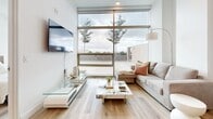 Located on Wilshire Boulevard in the heart of Los Angeles, this thoughtfully designed one-bedroom, one-bathroom residence offers a sleek, modern aesthetic across a single-floor layout. Light hardwood flooring flows seamlessly throughout, complementing the clean white walls and contemporary finishes that define the space.

The open-concept kitchen is a standout feature, showcasing rich dark wood cabinetry paired with quartz countertops, stainless steel appliances including a full-size refrigerator, and a center island that doubles as a breakfast bar. The kitchen connects naturally to the living area, which is bathed in natural light from expansive floor-to-ceiling windows offering open outdoor views of the Los Angeles skyline and surrounding trees.

The bedroom continues the home's modern character, featuring large floor-to-ceiling windows that flood the room with natural light and provide scenic outdoor views, creating a bright and tranquil retreat. A dedicated closet provides practical storage.

The full bathroom is well-appointed with dark wood floating vanity cabinetry, white quartz countertops, a large mirror, and a glass-enclosed tub-shower combination. Light pours in through a sizable window, enhancing the clean, spa-like atmosphere. Every detail of this residence reflects a cohesive, contemporary design sensibility ideal for urban living in Los Angeles.