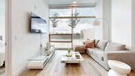 Located on Wilshire Boulevard in the heart of Los Angeles, this thoughtfully designed one-bedroom, one-bathroom residence offers a sleek, modern aesthetic across a single-floor layout. Light hardwood flooring flows seamlessly throughout, complementing the clean white walls and contemporary finishes that define the space.

The open-concept kitchen is a standout feature, showcasing rich dark wood cabinetry paired with quartz countertops, stainless steel appliances including a full-size refrigerator, and a center island that doubles as a breakfast bar. The kitchen connects naturally to the living area, which is bathed in natural light from expansive floor-to-ceiling windows offering open outdoor views of the Los Angeles skyline and surrounding trees.

The bedroom continues the home's modern character, featuring large floor-to-ceiling windows that flood the room with natural light and provide scenic outdoor views, creating a bright and tranquil retreat. A dedicated closet provides practical storage.

The full bathroom is well-appointed with dark wood floating vanity cabinetry, white quartz countertops, a large mirror, and a glass-enclosed tub-shower combination. Light pours in through a sizable window, enhancing the clean, spa-like atmosphere. Every detail of this residence reflects a cohesive, contemporary design sensibility ideal for urban living in Los Angeles.
