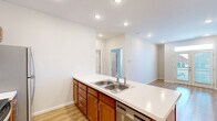 Located at 1221 W Allen St, Unit 203 in Bloomington, Indiana, this one-bedroom, one-bathroom residence offers a well-designed layout with modern finishes throughout. The open-concept living and kitchen area is anchored by a peninsula-style island with a white countertop and an integrated sink, providing both prep space and a natural gathering point. The kitchen is fully equipped with stainless steel appliances, including an electric range, over-the-range microwave, and a full-size refrigerator, all complemented by warm-toned wood cabinetry with brushed metal hardware. Light hardwood-style flooring runs through the main living areas and bathroom, adding warmth and cohesion to the space. Recessed lighting throughout the kitchen and living area ensures a bright, clean atmosphere. The bedroom features plush carpeting and a large window fitted with blinds that allows natural light to filter in while offering views of the surrounding neighborhood. A dedicated closet provides practical storage. The bathroom is clean and functional, featuring a full tub-shower combination, updated fixtures, and the same hardwood-style flooring found in the main living areas. The overall design is modern, neutral, and move-in ready.