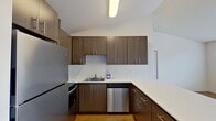 This 460 square foot apartment in Vancouver, WA offers a thoughtful layout that maximizes every inch of space. The single-level unit features one bedroom measuring 140 square feet, complemented by two full bathrooms for added convenience. The modern kitchen is a standout, boasting sleek wood-grain cabinetry, stainless steel appliances, and ample counter space with a peninsula that doubles as a dining area. Light wood-look flooring in the kitchen and living areas contrasts nicely with plush carpeting in the bedroom. Large windows in the living space and bedroom allow natural light to flood the apartment, creating an open and airy feel. The unit includes the convenience of in-unit laundry with a stacked washer and dryer. White walls, doors, and trim throughout provide a clean, neutral backdrop for personalization. This apartment efficiently combines functionality and style in a compact urban living space.