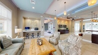 Located in Apopka, Florida, this single-story community clubhouse on Marden Ridge Loop offers a thoughtfully designed layout encompassing a living room, kitchen, game room, and office. The interior is unified by large-format ceramic tile flooring and a warm, neutral color palette throughout.

The welcoming living room features tray ceilings with soft blue accents, elegant pendant lighting, and comfortable patterned seating arranged around a rustic wood coffee table. Large windows along one wall fill the space with natural light and offer views of an outdoor pool area, with a glass door providing direct access.

The kitchen is outfitted with rich dark wood cabinetry, a sleek white quartz island, stainless steel appliances, and modern globe pendant lights, making it both functional and visually striking. An adjacent beverage station adds convenience for community gatherings.

The office area features a built-in workstation with multiple computer terminals and barstool seating, illuminated by a statement chandelier — ideal for productivity or remote work needs.

The game room is bright and inviting, with abundant natural light streaming through multiple windows. A full-size billiard table takes center stage, complemented by industrial-style pendant lighting, bistro tables, and cue racks mounted on the wall. Ceiling fans throughout the clubhouse ensure year-round comfort in the Florida climate.
