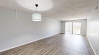 Located at The Palmer in Largo, Florida, this single-floor, three-bedroom, two-bathroom residence offers a well-organized layout across a comfortable footprint. The open living area welcomes you with wood-look plank flooring, neutral gray walls, a textured ceiling, and a stylish pendant light fixture. A sliding glass door floods the space with natural light and provides direct outdoor access with views of the surrounding greenery.

The kitchen is thoughtfully updated, featuring crisp white shaker cabinetry, gray quartz-style countertops, and a full suite of stainless steel appliances, including a range, over-the-range microwave, and refrigerator. Wood-look flooring continues throughout the kitchen, tying the common areas together cohesively.

Two hallways connect the living spaces to the three bedrooms, each carpeted for comfort and equipped with windows that bring in natural light. The spacious primary bedroom includes a sliding glass door providing additional outdoor access. Two closets offer practical storage solutions throughout the home.

Both bathrooms are finished in a clean, all-white palette with wood-look flooring, white vanity cabinetry, and shower-tub combinations — one with a tub/shower and one with a dedicated shower stall. The consistent, modern finishes throughout create a bright and cohesive living environment.