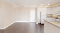 This single-floor unit offers a clean, functional layout with a consistent neutral color palette of warm beige tones and crisp white trim throughout. The open living area features dark hardwood-style flooring that extends into the kitchen and bathrooms, creating a cohesive and easy-to-maintain finish. Recessed lighting and a front entry door anchor the living space, which flows naturally into the kitchen. The kitchen is equipped with white cabinetry, granite-look countertops, a double stainless steel sink, a gas range, built-in microwave, and a full-size refrigerator. A window above the sink allows for natural light. The bedrooms are finished with plush wall-to-wall carpeting and fitted with horizontal window blinds that provide privacy while still admitting natural light. One bedroom benefits from dual windows, enhancing brightness and ventilation. Both bathrooms mirror each other in design, each featuring dark hardwood-style flooring, a white vanity with storage cabinetry, a large mirror, a tub-shower combination, and a window for natural light. The overall ambiance is clean, neutral, and move-in ready, offering a practical and comfortable living environment.