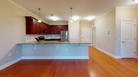 This single-floor residence in Maplewood, NJ offers a thoughtfully designed layout that balances open communal spaces with comfortable private quarters. The heart of the home is an open-concept kitchen and living area finished with warm hardwood flooring and crown molding. The kitchen is outfitted with rich cherry wood cabinetry, granite countertops, a subway tile backsplash, and stainless steel appliances including a gas range, built-in microwave, and refrigerator. A peninsula with pendant lighting above provides additional workspace and casual seating while connecting seamlessly to the living area.

The bedrooms are carpeted and finished with neutral tones, offering a quiet, comfortable atmosphere. Each room features windows with views of surrounding greenery, allowing natural light to fill the space. The bathrooms are well-appointed, one featuring a full tub-shower combination with subway tile surround, a cherry vanity with dark granite countertop, and tile flooring. A second bathroom provides a vanity with granite counters and tile flooring. A dedicated utility room houses a stacked washer and dryer alongside a water heater, offering practical in-unit convenience.