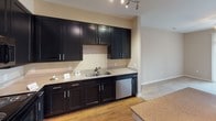Located at 300 Blue Sky Dr in Concord, NC, this single-floor unit offers a cohesive layout designed for comfortable everyday living. The kitchen serves as a functional centerpiece, showcasing dark espresso-toned cabinetry with brushed nickel hardware, granite-look countertops, and a full suite of stainless steel appliances including a refrigerator, range with oven, built-in microwave, and dishwasher. Wood-look flooring and track lighting enhance the kitchen's polished aesthetic, while ample upper and lower cabinet storage adds practicality.

The living area is finished with neutral carpet and features a ceiling fan, creating a relaxed atmosphere. A sliding glass door opens to an outdoor space, allowing natural light to fill the room. The bedroom mirrors this comfort with plush carpet, a ceiling fan, and a window with neighborhood views.

A hallway connects the main spaces, transitioning between wood-look and carpeted flooring. The bathroom is cleanly appointed with a tub-shower combination, a dark vanity with a white countertop, a framed mirror, and wood-look flooring. A dedicated laundry area includes a full-size washer and dryer beneath a wire storage shelf, completing the unit's practical amenities.