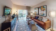 This single-floor residence offers a thoughtfully designed layout that balances comfort and functionality. The open-concept living area serves as the heart of the home, featuring light hardwood flooring, neutral gray walls, and a sliding glass door that opens to a private balcony with outdoor seating and pleasant greenery views. The living room provides ample space for relaxed entertaining, anchored by a warm leather sofa and accented by bold, colorful abstract artwork.

The kitchen is efficiently laid out with warm wood cabinetry, dark granite countertops, and a full suite of stainless steel appliances including a gas range, microwave, and refrigerator. Track lighting overhead and a peninsula counter enhance both the functionality and flow of the space.

The bedrooms are finished with plush carpeting and feature large windows that invite natural light. Each room offers closet storage, with the primary bedroom showcasing a dedicated walk-in closet. The neutral tones and understated design create a calm, restful atmosphere throughout.

The bathroom is finished with light ceramic tile flooring, a dark granite-topped vanity with rich wood cabinetry, and a full tub-shower combination. A built-in closet rod and curtained tub enclosure add a practical, polished touch. Overall, the residence presents a clean, modern aesthetic with warm accents throughout.