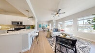 This thoughtfully designed 1-bedroom, 1-bathroom home offers a smart, open-concept floor plan that maximizes every square foot. Light-toned hardwood-style flooring flows seamlessly throughout, creating a cohesive and airy atmosphere. The living room is bright and inviting, featuring a ceiling fan, multiple windows with outdoor views, and ample space for comfortable seating arrangements. Adjacent to the living area, the dining room benefits from abundant natural light streaming through large windows and a glass door, lending an open, welcoming feel. The kitchen is well-appointed with white shaker cabinetry extending to the ceiling, a subway tile backsplash, stainless steel appliances including a side-by-side refrigerator and range, and a peninsula with bar seating — ideal for casual dining or entertaining. The spacious bedroom offers corner windows that frame outdoor views and fill the room with natural light. The full bathroom includes a tiled tub-shower combination, white vanity cabinetry, and clean, neutral finishes. A dedicated in-unit laundry area with side-by-side washer and dryer adds everyday convenience. A closet and hallway complete the practical layout, making this a functional and stylish home.