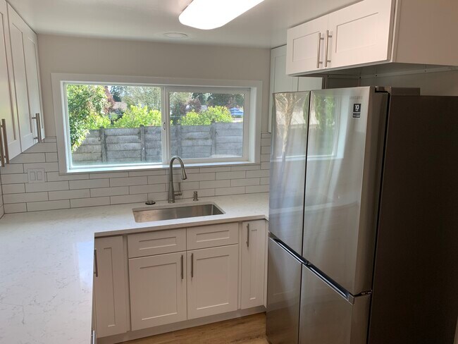 Cocina nueva con azulejos, encimeras de piedra y electrodomésticos de acero inoxidable. - 4018 NE 54th Ave