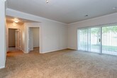 This single-floor residence offers a thoughtfully designed layout that balances comfort and functionality. The open living area is finished with plush wall-to-wall carpeting, crown molding, and a ceiling fan, creating a welcoming atmosphere. Large sliding glass doors flood the space with natural light and provide access to an outdoor area, while built-in shelving along one wall adds both character and practical storage.

The kitchen features light maple cabinetry, stone-finish countertops, and a suite of stainless steel appliances including a refrigerator, dishwasher, and range. Wood-look flooring ties the space together, and a breakfast bar peninsula opens the kitchen toward the living area for a connected feel.

The bedrooms are generously sized, carpeted for comfort, and receive ample natural light through large windows. Each bathroom is finished with wood-look flooring, maple vanity cabinetry, stone-finish countertops, and large mirrors. One bathroom includes a full tub-shower combination with white tile surround.

A dedicated in-unit laundry area houses a top-loading washer with overhead shelving, providing convenient everyday utility. Throughout the residence, a consistent palette of neutral tones and quality finishes contributes to a clean, cohesive aesthetic.