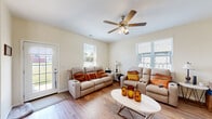 Located at 2400 Oakland Circle in Morris, IL, this two-story home offers three bedrooms and three bathrooms thoughtfully distributed across two well-proportioned floors. The main level features an open-concept kitchen and living area bathed in natural light from multiple windows. The kitchen is a standout, boasting rich dark wood cabinetry, black appliances, and a generous center island with a built-in sink and seating for several bar stools — ideal for both meal prep and casual dining. The spacious living room continues the warm aesthetic with light hardwood-style flooring, ceiling fans, and ample room for comfortable seating arrangements. A carpeted staircase with a clean white railing connects the two floors. The upper level houses the bedrooms, including a well-sized primary bedroom featuring hardwood-style flooring, a ceiling fan, and natural light from multiple windows. Each bedroom includes closet storage. The three bathrooms are consistently finished with warm wood vanities, white countertops, and hardwood-style flooring. Throughout the home, neutral wall tones and consistent flooring create a cohesive, welcoming atmosphere that carries from room to room.