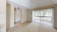Located in Bradenton, FL, this one-bedroom, one-bathroom unit offers a thoughtfully organized single-floor layout that maximizes its cozy footprint. The open kitchen is a functional highlight, featuring crisp white cabinetry, gray countertops, stainless steel appliances including an electric range with overhead ventilation, and durable wood-look flooring — providing an efficient and clean workspace. The combined kitchen and living area creates a seamless flow, with the living room offering plush carpeting, neutral warm-toned walls, and access to a sliding glass door that floods the space with natural light and provides views of the surrounding greenery. The spacious bedroom is outfitted with soft carpeting, a ceiling fan, a bright window overlooking outdoor vegetation, and a full-sized closet for ample storage. An additional closet is visible from the living area, adding practical storage options. The bathroom features tile flooring, a full vanity with a wide mirror and generous counter space, and a shower-tub combination. Textured ceilings are consistent throughout, lending a classic Florida residential character to the space. Overall, the unit presents a clean, neutral palette that offers a comfortable and functional living environment.