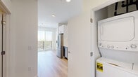 Located at 5259 Eliot St in Denver, CO, this efficiently designed one-bedroom, one-bathroom unit offers a thoughtfully arranged floor plan that maximizes every square foot. Light wood-tone flooring runs continuously throughout the space, creating a cohesive and clean aesthetic.

The kitchen is well-appointed with stainless steel appliances, including a gas range, dishwasher, and refrigerator. White subway tile backsplash, white upper cabinetry, and light wood lower cabinets provide a modern two-tone contrast, complemented by white quartz countertops. A stacked washer and dryer unit is conveniently housed in a dedicated closet just off the kitchen area.

The living and kitchen area opens toward a large sliding glass door that leads to a balcony, offering natural light and outdoor views. Recessed lighting provides additional illumination throughout.

The bedroom is a well-proportioned, bright room featuring a sliding frosted-glass door that opens to a dedicated closet with built-in rod storage. A window allows natural light to fill the space.

The bathroom features a full tub and shower combination with marble-style tile surround, light wood vanity with a white countertop, and light wood flooring, maintaining the modern and clean design language found throughout the unit.
