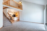 This well-designed two-story home in Madison, Wisconsin offers a thoughtful layout spread across two floors. The main level is anchored by an open-concept kitchen and living area, where light wood-tone flooring flows throughout. The kitchen is equipped with white cabinetry, black appliances including an electric range and refrigerator, light countertops, and a peninsula with a sink — ideal for both cooking and casual dining. The living area is bathed in natural light from a sliding glass door that opens to a private patio. A dedicated laundry room and convenient hallway storage round out the main floor. A wood-railed staircase leads to the upper level, where an open loft-style overlook adds to the home's sense of vertical space. The spacious primary bedroom features vaulted ceilings, plush carpeting, and a large walk-in closet with generous shelving. The second bedroom also offers carpeted floors, a standard closet, and a bright window with outdoor views. Both bathrooms are finished with tile flooring, vanity cabinetry, and mirrors. With five closets total throughout the home, storage is plentiful. The neutral color palette and clean finishes create a bright, welcoming ambiance throughout.