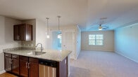 Located at 1001 Aventine Dr in Arden, NC, this one-bedroom, one-bathroom residence offers a well-organized, single-floor layout that efficiently combines comfort and functionality. The open-concept kitchen flows seamlessly into the living area, creating a cohesive and inviting space. The kitchen is highlighted by rich dark wood cabinetry, granite countertops with a tile backsplash, stainless steel appliances including a refrigerator, range, and microwave, and pendant lighting over a central island with a stainless steel sink. Hardwood-style flooring anchors the kitchen and entry areas, while plush carpet extends through the living room and bedroom. The spacious living room benefits from natural light through wide windows with blinds and is equipped with a ceiling fan. The bedroom offers a comfortable retreat with a ceiling fan, a large window, and mirrored sliding closet doors. The unit includes three closets in total, providing ample storage throughout. The bathroom features a tub/shower combination, a vanity with dark wood cabinetry, and hardwood-style flooring. A dedicated laundry area and hallway complete the practical layout of this well-appointed Arden residence.