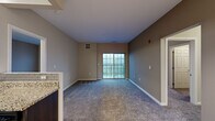 This 2-bedroom, 2-bathroom residence is thoughtfully designed across a single floor, offering a practical and cohesive layout. The combined kitchen and living area serves as the heart of the home. The kitchen features dark espresso cabinetry, granite-style countertops, a subway tile backsplash, stainless steel appliances including a refrigerator, range, and built-in microwave, and durable tile flooring. The adjacent living room is carpeted and bathed in natural light, with a sliding glass door opening to a private balcony with outdoor views. The generously sized primary bedroom features plush carpet, warm neutral tones, and a large window that brings in natural light. The second bedroom is equally comfortable, also finished with carpet and neutral walls. Both bathrooms are finished consistently with tile flooring, dark vanity cabinetry, granite-style countertops, and mirrored medicine cabinets. A dedicated in-unit laundry area with full-size washer and dryer adds everyday convenience. Two closets and a hallway complete the layout. Throughout the space, neutral warm tones, clean white trim, and consistent finishes create a cohesive and inviting ambiance.