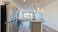 Located at 210 W Fifth Ave in Columbus, Ohio, this contemporary single-floor residence offers a thoughtfully designed open-concept layout that maximizes both function and comfort. The kitchen serves as the centerpiece of the living area, showcasing gray cabinetry, granite countertops, a full suite of stainless steel appliances including a refrigerator, range, and microwave, and a central island with an undermount sink. Elegant pendant lighting above the island adds a polished touch, while recessed ceiling lights illuminate the space throughout. Light-toned wood-style flooring flows seamlessly through the kitchen and main living area, creating a clean, cohesive aesthetic. The living area receives natural light through a large window with views to an outdoor balcony. The bedroom is generously proportioned, carpeted for comfort, and features a large window that brings in abundant natural light. Adjoining the bedroom is a spacious walk-in closet with built-in wire shelving, offering ample storage. The bathroom is finished with wood-look tile flooring, a granite-topped vanity, and a stand-up shower enclosed with a glass door. The overall design balances modern finishes with a neutral palette, creating a bright and inviting atmosphere throughout.