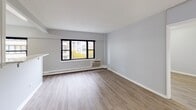 Located at 5815 N Sheridan Road in Chicago's vibrant Edgewater neighborhood, this single-floor unit offers a clean, modern aesthetic throughout. The layout is thoughtfully arranged, with open living areas that flow naturally from one space to the next.

The main living area is spacious and bright, featuring light hardwood-style flooring, soft gray walls, and large windows that frame views of the surrounding tree-lined streetscape and neighboring buildings. A wall-unit air conditioner and baseboard heating ensure year-round comfort. The living space connects seamlessly to an additional room, which also features hardwood-style floors, natural light, and generous proportions — suitable for use as a bedroom or flex space.

The kitchen is well-appointed with rich dark-toned cabinetry, white quartz countertops, a stainless steel refrigerator, and a black electric range. A pass-through window with a breakfast bar shelf connects the kitchen to the living area, enhancing the open feel of the unit. A walk-in closet is accessible from the living area, offering ample storage.

The bathroom is neatly finished with tile flooring, a soaking tub and shower combination with decorative tile accents, a pedestal sink, a mirrored medicine cabinet with vanity lighting, and a standard toilet. The overall atmosphere of the unit is clean, contemporary, and move-in ready.