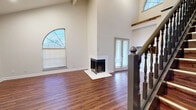 Located on Marvin Loving Dr in Garland, TX, this two-story, two-bedroom, two-bathroom home offers a well-designed layout spread across two floors. The main floor, which comprises the larger portion of the home, features a welcoming entryway with soaring vaulted ceilings and a staircase with a decorative banister. The living room is a standout space, highlighted by a white marble-surround fireplace and a striking arched window that floods the area with natural light. Rich hardwood-style flooring runs throughout the home, adding warmth and continuity. The kitchen is well-appointed with gray cabinetry, white countertops, a double-basin sink, and a charming arched window above. It also features a dishwasher and range. The primary bedroom is generously sized, with access to a dedicated closet and a private en-suite bathroom featuring a soaking tub set within an arched alcove, a vanity with a white countertop, and hardwood-style flooring. The second bathroom offers a full tub-shower combo. Upstairs, the second bedroom includes a ceiling fan and a private entry door. Each bedroom benefits from ceiling fans and natural light through windowed openings, making the home feel bright and comfortable throughout.