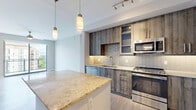 Located in Doral, FL, this well-appointed residence offers three bedrooms, three bathrooms, and two closets across a single thoughtfully designed floor. The open-concept kitchen and living area serves as the heart of the home, showcasing wood-look flooring, a granite-topped island with pendant lighting, rustic wood cabinetry, a tile backsplash, and a full suite of stainless steel appliances including a built-in microwave, range, dishwasher, and refrigerator. The kitchen flows seamlessly into the living area, which is bathed in natural light from large sliding glass doors that open to a private balcony overlooking lush tropical landscaping and neighboring architecture. The bedrooms feature plush carpeting, ceiling fans, and large windows that bring in ample daylight. The spacious primary bedroom includes a walk-in closet with built-in shelving and hanging rods for generous storage. The bathrooms are finished with large-format tile flooring, granite-topped wood vanities, oversized mirrors, and glass-enclosed showers, offering a clean, spa-like aesthetic. Neutral tones and modern finishes throughout create a cohesive and contemporary ambiance.