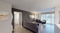 This single-floor residence offers a thoughtfully designed layout with a cohesive modern aesthetic. The living room serves as the central gathering space, featuring warm wood-look flooring, a bold dark gray accent wall, and a large sliding glass door that invites natural light and provides outdoor views. The open arrangement comfortably accommodates a seating area and flows naturally into the rest of the unit.

The kitchen is well-equipped with stainless steel appliances, including a range, microwave, and refrigerator. White shaker-style cabinetry, a mosaic tile backsplash, and a dark island with a light countertop provide both functionality and visual contrast. A tall pantry cabinet adds generous storage.

Two bedrooms offer comfortable retreats, each with plush carpeting, vertical blinds on windows that allow natural light, and dedicated closet space. One bedroom includes a walk-in closet, while both rooms provide ample room for furnishings.

The two bathrooms are finished with dark vanity cabinetry and granite-style countertops. One bathroom features a tub-shower combination with white tile surround, while the other offers a glass-enclosed shower with wood-look flooring, rounding out this well-balanced residence.