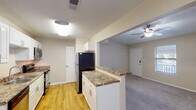 Located in Gulf Breeze, Florida, this single-floor residence offers a thoughtfully designed 2-bedroom, 2-bathroom layout ideal for comfortable everyday living. The open-concept living area features plush carpeting, a ceiling fan with light fixture, and a pass-through connection to the kitchen, creating a bright and cohesive common space. The front entry opens directly into the living area, which benefits from natural light through blinded windows.

The galley-style kitchen is well-appointed with white cabinetry, granite-look countertops, and stainless steel appliances including a range, microwave, dishwasher, and refrigerator. Wood-look flooring runs throughout the kitchen, adding warmth and easy maintenance underfoot.

Both bedrooms are carpeted and feature ceiling fans, windows with blinds, and ample wall space. Each bathroom is equipped with granite-look vanity countertops and white cabinetry. One bathroom includes a tub-shower combo, while the primary bath offers a separate vanity area with a wide mirror and a walk-in shower/tub combination. A textured ceiling finish is consistent throughout the home, complementing the neutral warm-beige color palette that gives the entire residence a clean, move-in-ready feel.