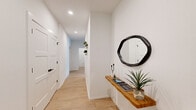 This well-designed single-story home offers three bedrooms and three bathrooms within a thoughtfully laid-out floor plan. The open-concept kitchen and living area serves as the heart of the home, featuring dark charcoal cabinetry with sleek hardware, stainless steel appliances including a French door refrigerator, a subway tile backsplash, and granite countertops. A dedicated dining area sits adjacent to the kitchen, making it ideal for everyday meals or entertaining. The living room is bright and airy, with a ceiling fan, large windows dressed with horizontal blinds, and light wood-style flooring that runs throughout the entire home. Multiple hallways connect the rooms, with recessed lighting and clean white walls that contribute to the home's modern, minimalist aesthetic. A built-in entryway shelf with a decorative mirror adds a welcoming touch at the entrance. Each bedroom offers a comfortable and functional space, with individual mini-split HVAC units ensuring climate control. The three bathrooms are consistently appointed with white cabinetry, granite-topped vanities, glass-enclosed tiled showers, and matte black fixtures and hardware, delivering a cohesive modern style. Light wood flooring and crisp white walls unify the space throughout.