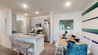 Located at 1730 Northpointe Pkwy in Lutz, Florida, this single-floor residence presents a cohesive, modern interior with consistent finishes throughout. The kitchen is a functional centerpiece, featuring gray shaker-style cabinetry, granite countertops, stainless steel appliances including a refrigerator, range, and microwave, and wood-look plank flooring. A kitchen island with seating provides additional workspace and casual dining.

The open dining area adjoins the kitchen and is distinguished by bold navy and green horizontal striped walls, a design element that continues into the living room, creating a vibrant, connected aesthetic. The living room offers generous seating space, a ceiling fan, and glass French doors that invite natural light and provide outdoor access.

The bedrooms feature plush carpeting and natural light from well-placed windows. Each room carries its own accent wall design, adding visual character. The bathrooms are finished with granite-topped gray vanities, wood-look flooring, and tub-shower combinations. The layout, as seen in the 3D overview, flows logically between living, dining, kitchen, bedroom, and bathroom spaces, offering a well-organized and comfortable living environment.