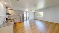 Located at 401 N 1st St in Rogers, Arkansas, this modern one-bedroom, one-bathroom unit offers a well-designed layout across a single floor. Light hardwood flooring runs throughout the entire space, creating a cohesive and clean aesthetic.

The open-concept kitchen and living area serves as the heart of the unit. The kitchen is outfitted with flat-front white cabinetry extending to the ceiling for maximum storage, a white subway tile backsplash, granite countertops, and a full suite of stainless steel appliances including a range with hood vent, dishwasher, and refrigerator. A pendant light fixture accents the space above.

The bedroom is comfortably sized with large windows that invite natural light and offer views of surrounding greenery and the neighborhood streetscape. A ceiling fan adds to the room's functionality. Crisp white walls and light flooring give the bedroom a bright, airy feel.

The bathroom features granite countertops, muted teal-toned cabinetry with matte black hardware, and a walk-in shower. Conveniently adjacent to the bathroom is an in-unit stacked washer and dryer. Additional storage is provided by a dedicated walk-in closet. The unit's clean lines, modern finishes, and practical layout make it a well-appointed urban residence in downtown Rogers.