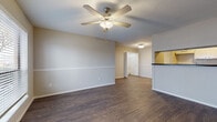 This single-story, 2-bedroom, 2-bathroom residence offers a practical and cohesive layout unified by rich, dark hardwood-style flooring that runs throughout every room. The open living area is spacious and bright, featuring a ceiling fan with light kit, a decorative chair rail along neutral-toned walls, and a large window that invites natural light and outdoor views. The layout flows naturally from the living space toward a galley-style kitchen, which is well-equipped with white cabinetry, dark speckled countertops, a double sink, and white appliances including a range, dishwasher, and refrigerator.

Both bedrooms are comfortably sized, each offering a ceiling fan, a window with blinds for natural light and privacy, and neutral walls that provide a calm, versatile backdrop. The two bathrooms are finished consistently with white cabinetry, dark speckled countertops, and single-basin sinks. One bathroom features a full shower-tub combination with white tile surround, while the other is accessible directly from a bedroom. Clean white trim and baseboards throughout contribute to a tidy, uniform aesthetic across the entire residence.