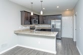 Located at 58880 Van Dyke Rd in Washington, Michigan, this two-story property offers a clean, modern aesthetic with a neutral color palette and quality finishes throughout. The main level features an open-concept layout where the living area flows seamlessly into the kitchen and dining space. The living room is finished with durable wood-look luxury vinyl plank flooring, recessed lighting, and a bright window with blinds, creating a welcoming and versatile space. A staircase along one wall provides access to the upper level. The kitchen is a standout feature, equipped with rich, dark espresso cabinetry, granite countertops, stainless steel appliances including a refrigerator with ice maker and a microwave, and a peninsula with pendant lighting overhead — ideal for casual dining or meal prep. The bathroom features tile flooring, a full tub-shower combination with white tile surround, a dark vanity with granite countertop, and brushed nickel hardware. Upper-level bedrooms are carpeted for comfort and receive natural light through windows with blinds. Throughout the property, crisp white trim and doors provide clean contrast against the warm neutral walls, contributing to a cohesive and polished interior design.