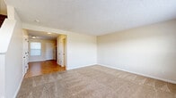 Located in Columbus, Ohio, this two-story home offers a practical and comfortable layout across two floors. The main level features a combined dining room and kitchen equipped with warm honey-toned cabinetry, dark granite-style countertops, black appliances including a gas range, built-in microwave, refrigerator, and dishwasher, all set atop wood-look flooring. The living room is generously sized with plush carpeting, neutral walls, and a textured ceiling, while a staircase leads to the upper level. A half bath on the main floor features hardwood-style flooring, a warm wood vanity with dark countertop, and a framed mirror. A patio provides convenient outdoor access. Upstairs, the spacious primary bedroom features wall-to-wall carpet, a closet, and a textured ceiling. The second bedroom is equally well-sized with neutral carpeting and ample natural light. Two full bathrooms on the upper level mirror the warm wood vanity aesthetic found throughout, each with dark countertops and hardwood-style flooring. Six closets are distributed throughout the home, offering exceptional storage. A dedicated laundry room and utility room add further functionality to this well-designed residence.