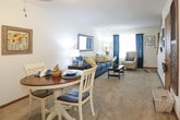 This two-floor residence offers a well-organized layout designed for comfortable everyday living. The main living area is carpeted and features a ceiling fan overhead, creating a relaxed atmosphere that flows naturally into an adjacent dining space. The dining area accommodates a round table and is anchored by a ceiling fan as well, with easy access to a galley-style kitchen. The kitchen is finished with tile flooring, laminate countertops, wood-trimmed cabinetry, and black appliances, providing a practical and efficient workspace.

The living room is a welcoming space with neutral walls, carpet flooring, and room for comfortable seating arrangements. A large framed mirror adds visual depth to the room.

Multiple bedrooms are spread across the layout, each carpeted and finished with neutral walls. One bedroom features a window with curtains that allow natural light to filter in, along with a ceiling fan. Another bedroom includes mirrored sliding closet doors, offering generous storage. Each bedroom maintains a calm, understated aesthetic.

The bathroom is finished with tile flooring, a shower-tub combination, and a vanity with wood-toned cabinetry. Throughout the space, consistent use of carpet, neutral tones, and wood accents creates a cohesive and functional interior.