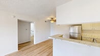 Located on Doolittle Avenue in Riverside, California, this single-floor, one-bedroom, one-bathroom unit offers a well-organized layout designed for comfortable everyday living. The combined kitchen and living area forms the heart of the home, where light wood-style flooring runs throughout, creating a clean, cohesive aesthetic. The kitchen is efficiently designed with abundant white cabinetry providing generous storage, stainless steel appliances including a refrigerator and dishwasher, a black gas range with an overhead ventilation hood, and a marble-style countertop that extends to a peninsula — ideal for casual dining or meal prep. A ceiling fan overhead adds to the comfort of the living area, which opens directly to a private patio through a sliding glass door, bringing in natural light and outdoor access. The bedroom is a comfortable, carpeted retreat featuring a window with vertical blinds that invite natural light and views of the surrounding greenery. The bathroom is spacious and bright, finished with light wood-style flooring, a wide vanity with a marble-style countertop, a bathtub, and accessibility grab bars. A hallway connects the rooms, completing this thoughtfully arranged and well-lit single-story residence.