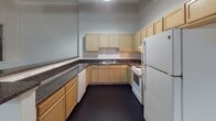 Located at 700 Stockton St in Richmond, Virginia, this single-floor space blends industrial character with functional living. The open main area immediately draws attention with its exposed wooden ceiling beams, painted brick walls, and visible ductwork — details that give the space a raw, loft-like aesthetic. Dark-stained concrete flooring runs consistently throughout, anchoring the industrial design language.

The kitchen is well-equipped and thoughtfully laid out in a U-shaped configuration, offering generous counter space with dark granite-style countertops, light wood cabinetry, a double sink, a dishwasher, electric range, and a full-size refrigerator. A pass-through counter connects the kitchen to the main living area, enhancing the open flow of the space.

The private rooms feature clean white walls, dark flooring, and exposed HVAC ducts, maintaining the industrial aesthetic while providing versatile enclosed spaces. The bathroom is straightforward and functional, finished in white with a pedestal sink, a large mirror with vanity lighting, and a full bathtub/shower combination. A warm wood-toned door adds a touch of contrast to the otherwise neutral palette.

Overall, the space offers a distinctive industrial character with practical amenities, making it well-suited for a variety of uses in the heart of Richmond.