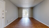 This single-story unit in Arlington, Texas offers a practical and efficiently arranged floor plan across a compact footprint. The living room serves as the central gathering space, finished with warm wood-look flooring, neutral gray walls, and a textured ceiling. A ceiling fan provides overhead lighting and air circulation. A sliding glass door fitted with vertical blinds allows natural light to enter and provides access to an outdoor area, adding a sense of openness to the space.

The galley-style kitchen is thoughtfully equipped with white shaker-style cabinetry featuring black hardware, white countertops, and wood-look flooring that continues from the living area. Black appliances, including a range, refrigerator, and dishwasher, provide functional contrast against the bright cabinetry. An over-the-range microwave adds convenience.

The bedroom offers a comfortable footprint with matching wood-look flooring, a ceiling fan with light fixture, a window for natural light, and access to a dedicated closet. The full bathroom includes a white tub-shower combination, overhead cabinetry for storage, and consistent wood-look flooring. Throughout the unit, neutral gray walls and white trim create a clean, cohesive aesthetic.