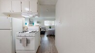 Located on Vanowen Street in Van Nuys, Los Angeles, this efficiently designed single-floor unit offers a bright and functional layout that maximizes every square foot. The open-concept living area is finished with light wood-look flooring throughout, creating a clean and cohesive aesthetic. White walls and a textured ceiling enhance the sense of openness, while a wall-mounted AC unit ensures year-round comfort. A large window floods the space with natural light and offers a pleasant view of surrounding greenery, adding a touch of the outdoors to the interior. The living area comfortably accommodates a full seating arrangement, making it a welcoming and practical space for everyday living. The kitchenette is equipped with a white gas range, overhead ventilation hood, and white cabinetry, providing essential cooking amenities in a compact footprint. A breakfast bar with seating connects the kitchen to the living area, adding both functionality and a social element to the layout. The bathroom features a full-sized soaking tub and shower combination, elegantly framed by marble-style surround walls in warm beige tones, offering a clean and polished finish. This unit delivers a practical and well-appointed living experience in a convenient Los Angeles location.