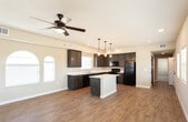 Located at 802 W Cherry Ln in Carlsbad, New Mexico, this single-story home offers a well-designed open-concept layout that seamlessly connects the kitchen, dining, and living areas. The kitchen is a standout feature, equipped with dark espresso cabinetry, a white countertop island, pendant lighting, recessed lighting, and a full suite of black appliances including a refrigerator, range, microwave, and dishwasher. A distinctive arched window floods the kitchen with natural light, complementing the warm wood-look flooring that runs throughout the main living areas. The spacious living room continues the open feel, highlighted by a ceiling fan, multiple windows with blinds, and arched architectural window detailing that adds character to the space. The bathroom is appointed with dark cabinetry, a white vanity countertop, a framed mirror, and wood-look flooring consistent with the rest of the home. Bedrooms feature plush carpeting, ceiling fans, natural light from windows, and closets with built-in shelving for ample storage. The neutral wall tones and clean finishes throughout create a bright, cohesive aesthetic suited for comfortable everyday living.