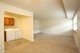 Located at 272 W Bay Ave in Norfolk, Virginia, this single-floor unit offers a practical and comfortable layout designed for everyday living. The open living area is finished with plush wall-to-wall carpeting and neutral cream-toned walls, creating a bright and welcoming atmosphere. A wide window allows natural light to fill the space, adding to its airy feel. The layout flows seamlessly into a galley-style kitchen, which is outfitted with warm wood cabinetry, granite-look countertops, black appliances including a gas range and refrigerator, a stainless steel sink, and light wood-look flooring that adds a clean, modern contrast. Additional storage is conveniently accessible from the kitchen area. The bedroom is generously proportioned, also featuring soft carpeting and neutral walls, and benefits from a large walk-in closet complete with built-in shelving and dual hanging rods for ample organization. The bathroom is finished with classic white tile, a pedestal-style sink, and a full soaking tub with shower, maintaining a clean and functional aesthetic throughout. The unit's straightforward single-level design ensures ease of navigation, while its consistent neutral palette and practical finishes provide a versatile canvas for any interior style.